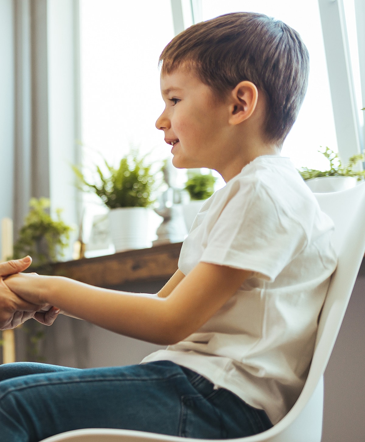 Torrance ASD treatment child sitting, smiling, holding hands with adult.