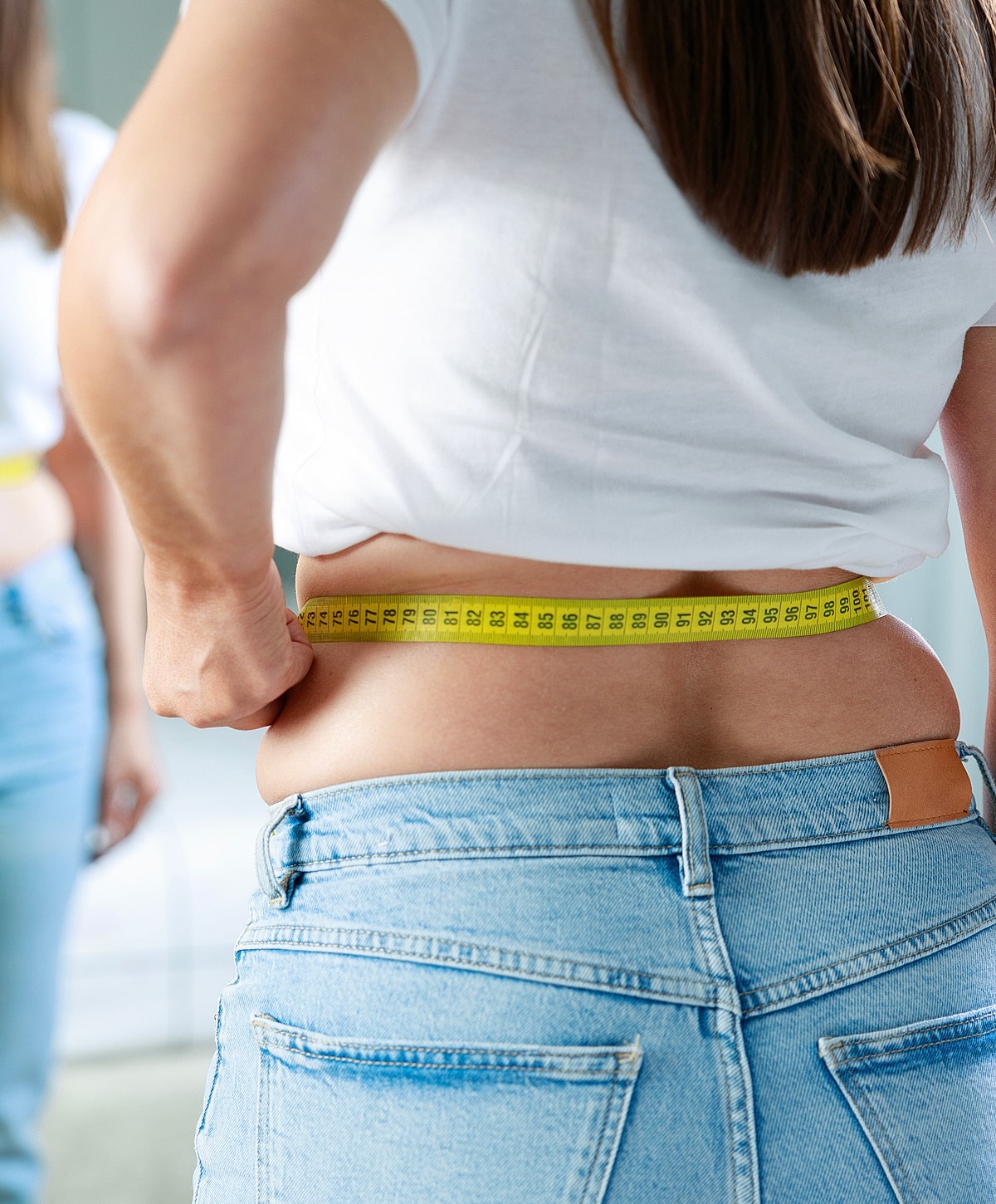 Torrance obesity treatment person measuring waist with a tape measure in mirror.