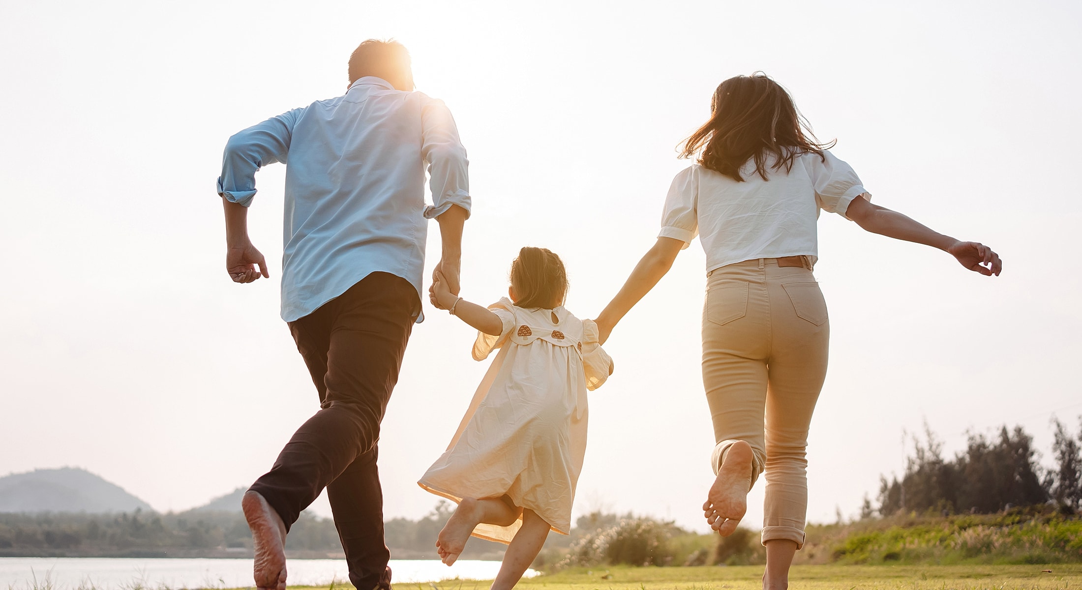 Family running together by the water at sunset.