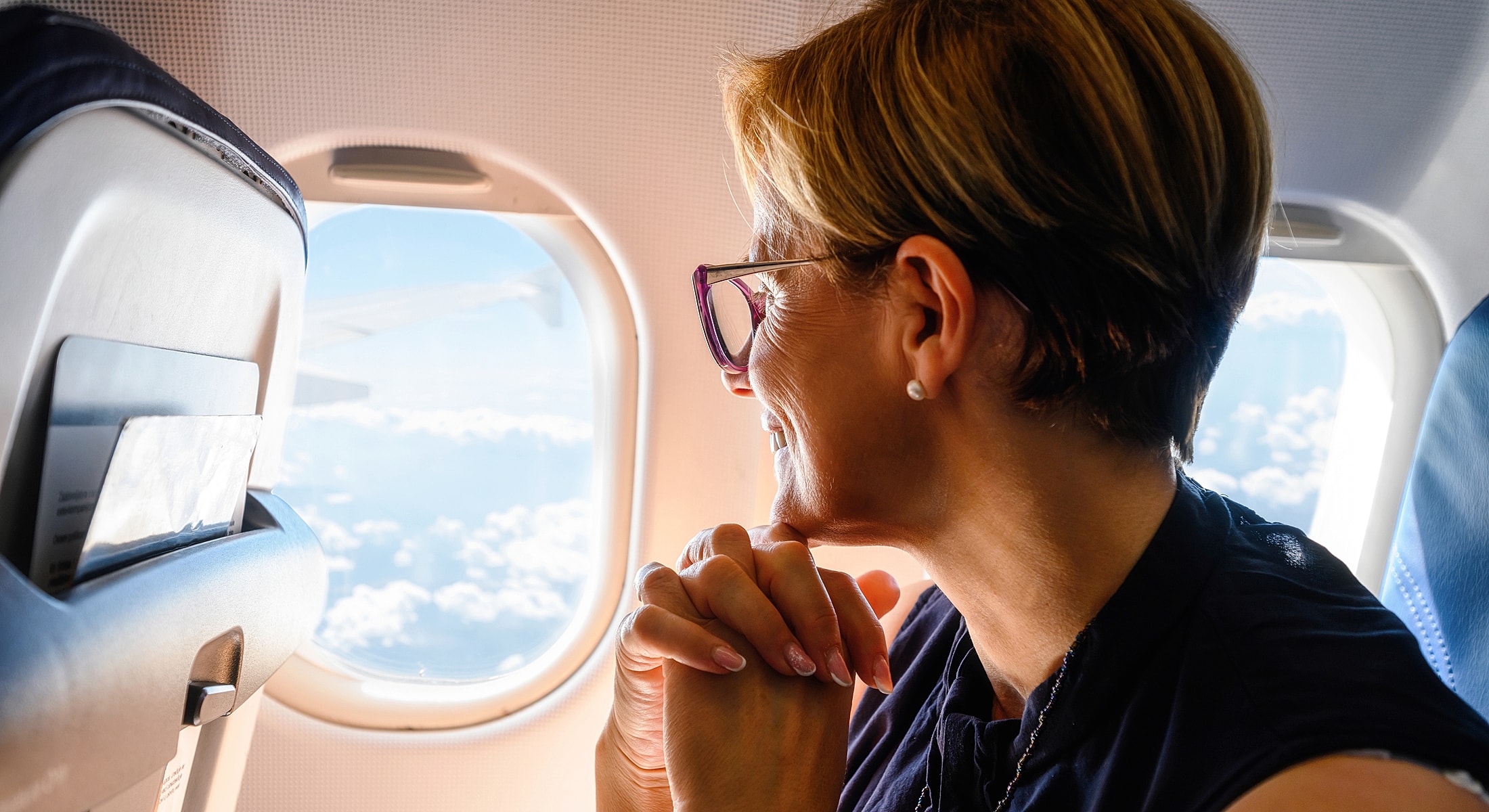 Passenger admiring clouds through airplane window.